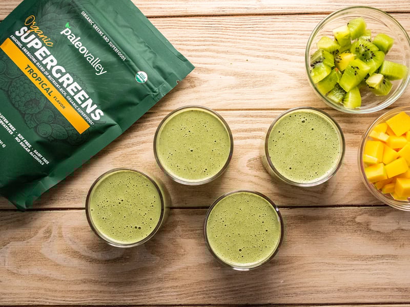 Tropical green coconut milk panna cotta made with Paleovalley Organic Supergreens, shown in glass cups with fresh kiwi and mango on the side.
